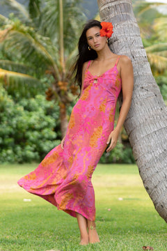 woman wearing a pink spaghetti strap maxi dress with a knot bust with lei print