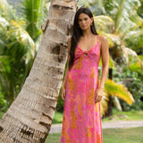 woman wearing a pink spaghetti strap maxi dress with a knot bust with lei print