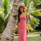 woman wearing a pink spaghetti strap maxi dress with a knot bust with lei print