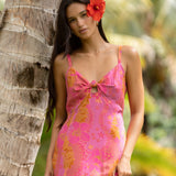 woman wearing a pink spaghetti strap maxi dress with a knot bust with lei print
