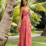 woman wearing a pink spaghetti strap maxi dress with a knot bust with lei print
