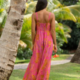 woman wearing a pink spaghetti strap maxi dress with a knot bust with lei print