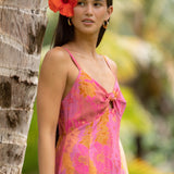woman wearing a pink spaghetti strap maxi dress with a knot bust with lei print