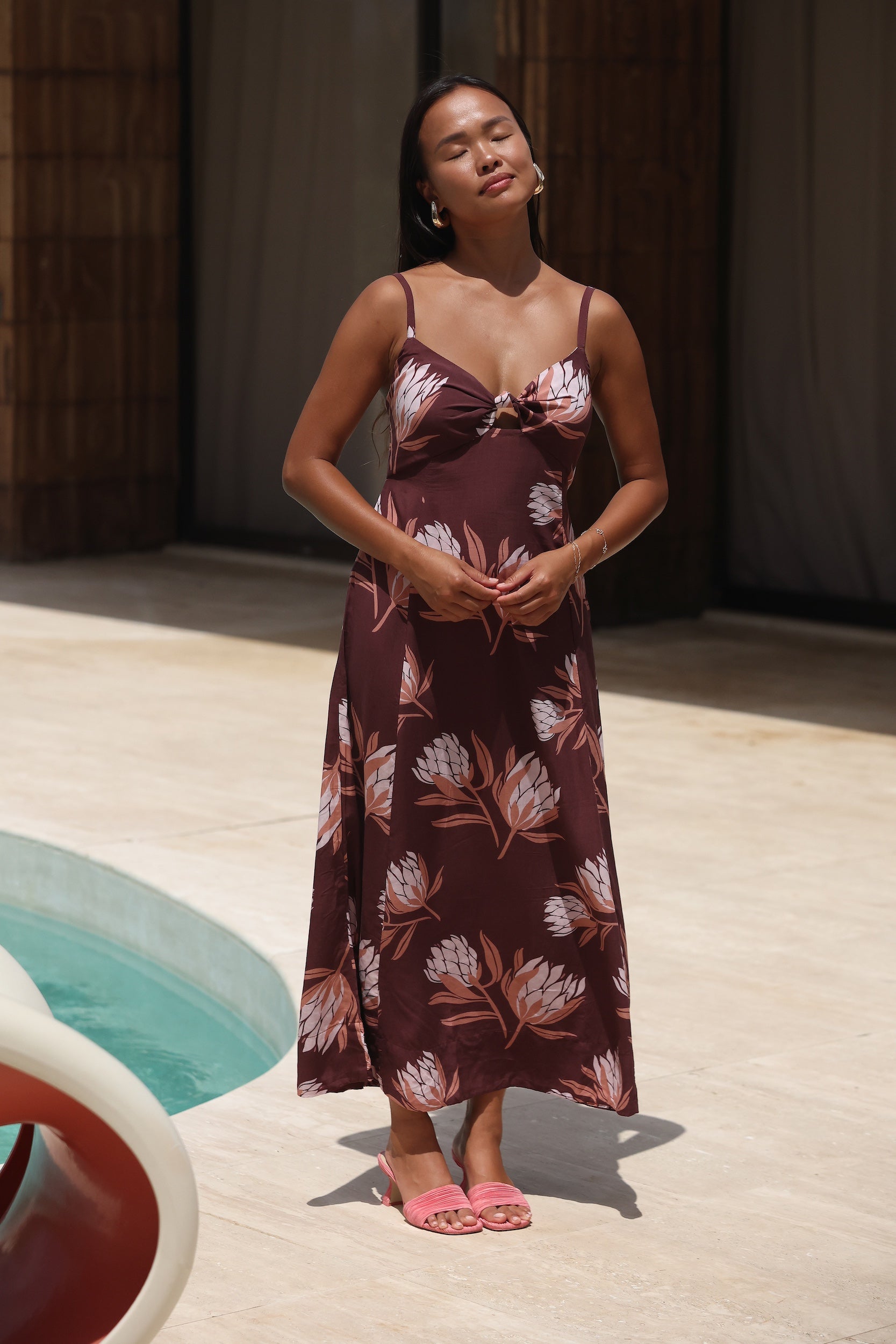 woman wearing a brown maxi dress with knot detail and protea print