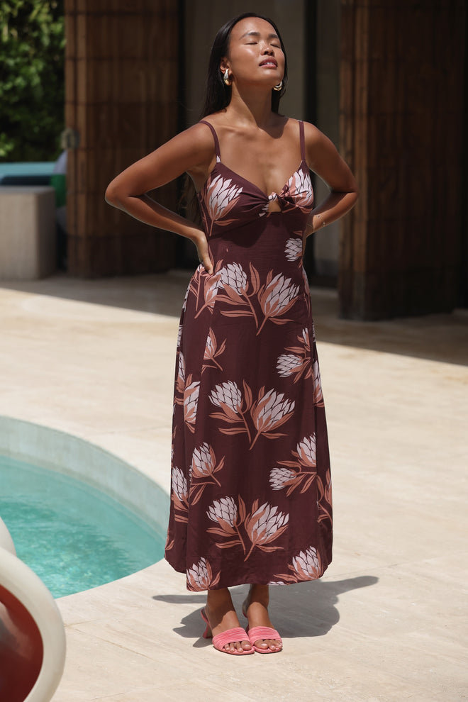 woman wearing a brown maxi dress with knot detail and protea print