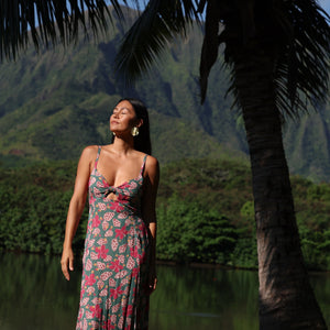 woman with brown hair wearing a teal maxi dress wth tie knot detail and shell and pua pattern