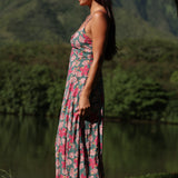 woman with brown hair wearing a teal maxi dress wth tie knot detail and shell and pua pattern