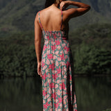 woman with brown hair wearing a teal maxi dress wth tie knot detail and shell and pua pattern