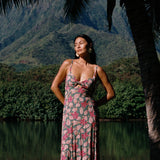 woman with brown hair wearing a teal maxi dress wth tie knot detail and shell and pua pattern