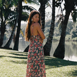 woman with brown hair wearing a teal maxi dress wth tie knot detail and shell and pua pattern