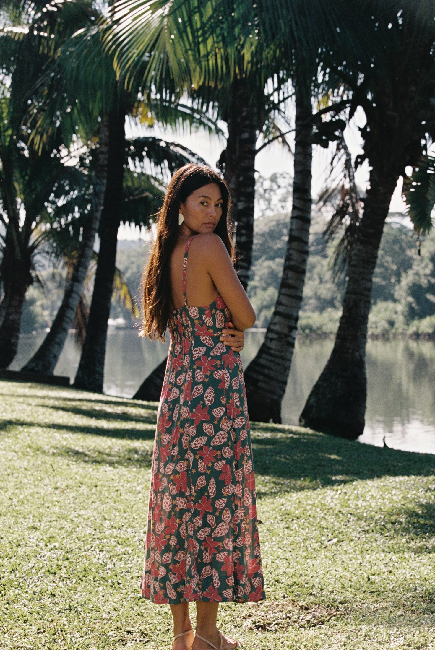 woman with brown hair wearing a teal maxi dress wth tie knot detail and shell and pua pattern