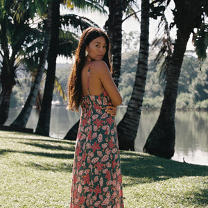 woman with brown hair wearing a teal maxi dress wth tie knot detail and shell and pua pattern