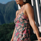 woman with brown hair wearing a teal maxi dress wth tie knot detail and shell and pua pattern