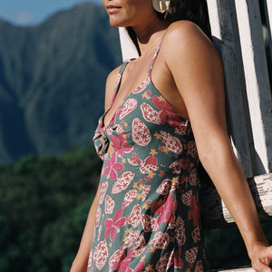 woman with brown hair wearing a teal maxi dress wth tie knot detail and shell and pua pattern