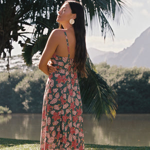 woman with brown hair wearing a teal maxi dress wth tie knot detail and shell and pua pattern