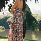 woman with brown hair wearing a teal maxi dress wth tie knot detail and shell and pua pattern