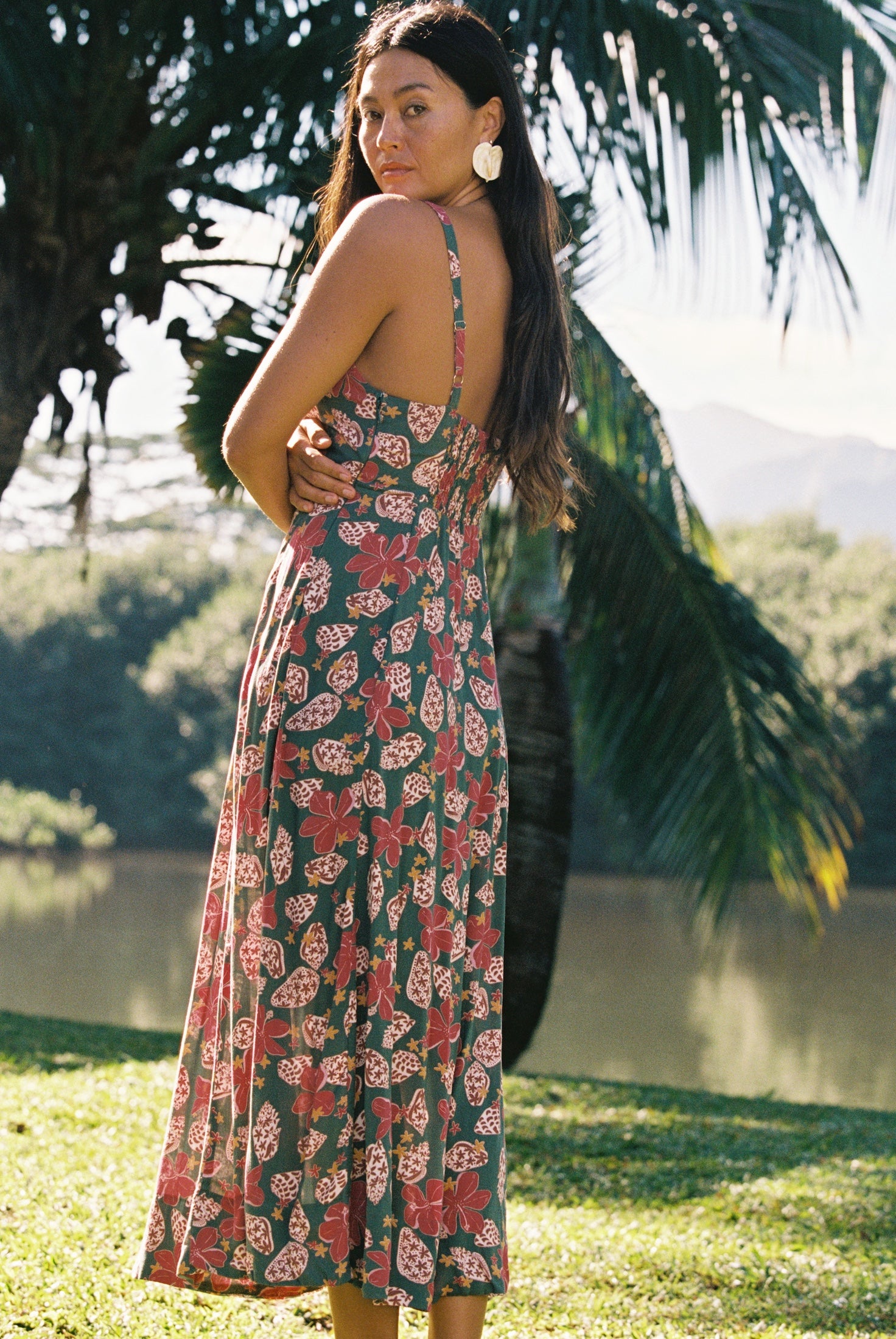 woman with brown hair wearing a teal maxi dress wth tie knot detail and shell and pua pattern