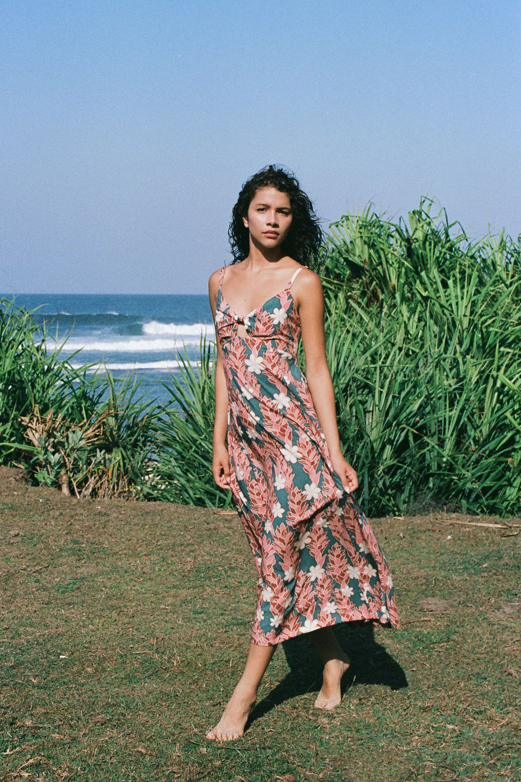 woman with brown hair wearing wearing a long maxi dress with knot tie neckline in a red ginger and tiare print