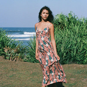 woman with brown hair wearing wearing a long maxi dress with knot tie neckline in a red ginger and tiare print