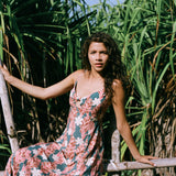 woman with brown hair wearing wearing a long maxi dress with knot tie neckline in a red ginger and tiare print