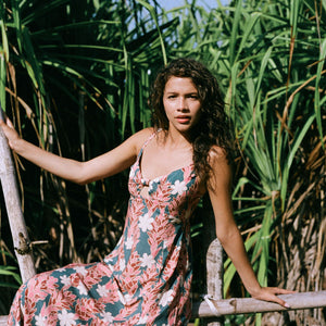 woman with brown hair wearing wearing a long maxi dress with knot tie neckline in a red ginger and tiare print