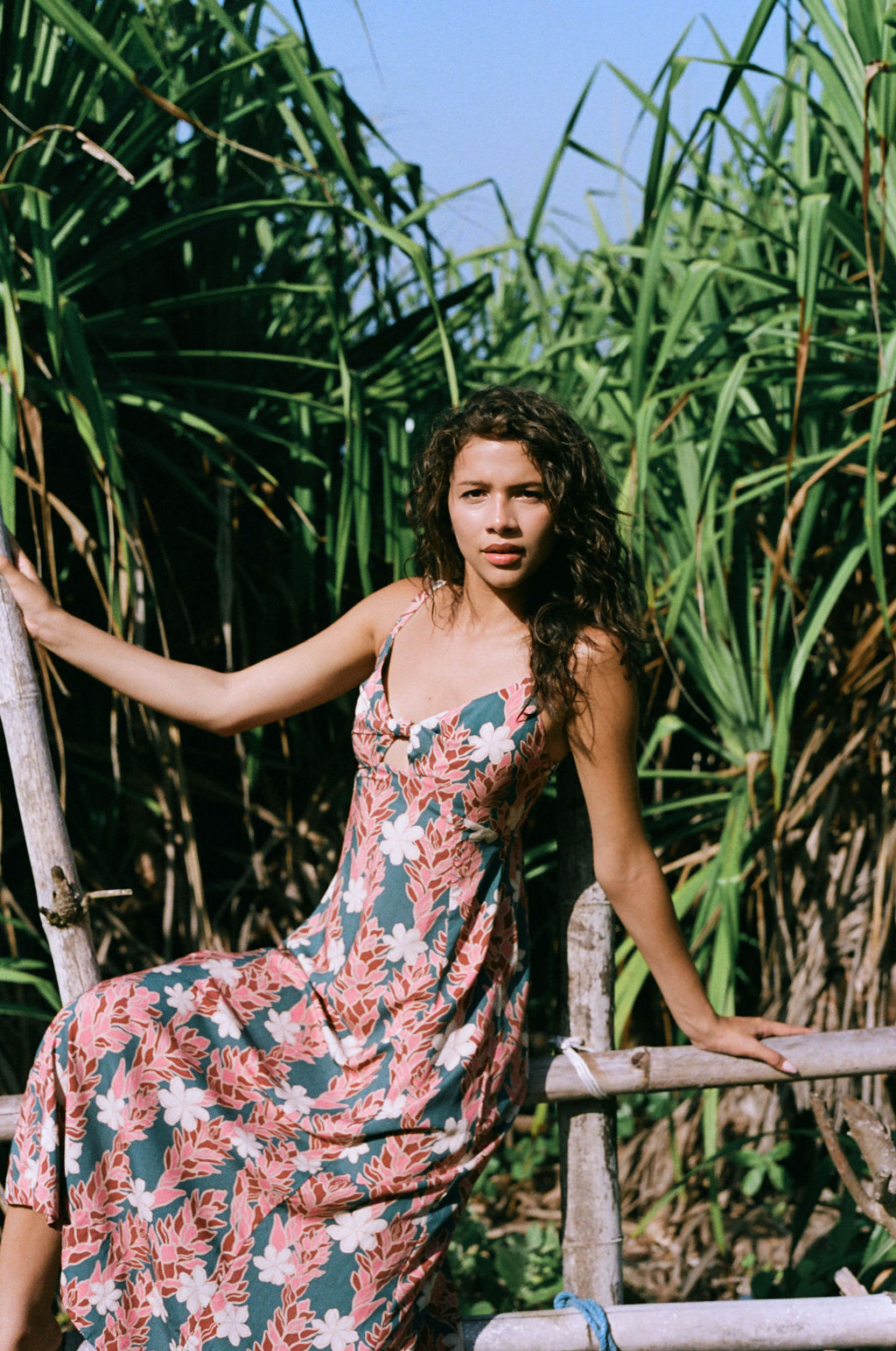 woman with brown hair wearing wearing a long maxi dress with knot tie neckline in a red ginger and tiare print