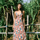 woman with brown hair wearing wearing a long maxi dress with knot tie neckline in a red ginger and tiare print