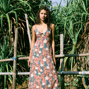 woman with brown hair wearing wearing a long maxi dress with knot tie neckline in a red ginger and tiare print