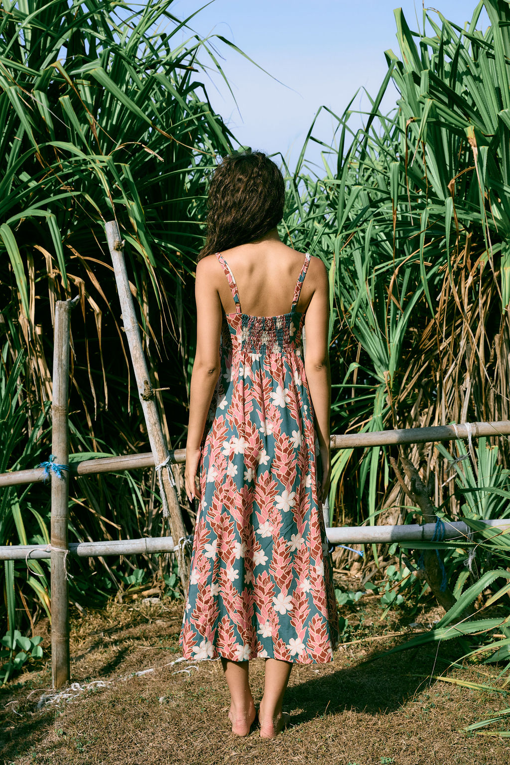 woman with brown hair wearing wearing a long maxi dress with knot tie neckline in a red ginger and tiare print