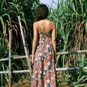woman with brown hair wearing wearing a long maxi dress with knot tie neckline in a red ginger and tiare print