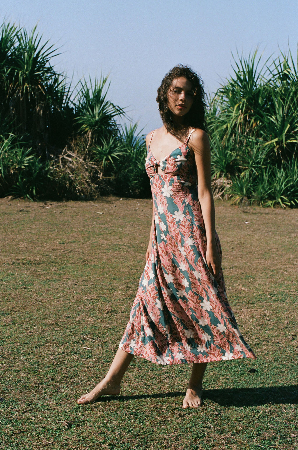 woman with brown hair wearing wearing a long maxi dress with knot tie neckline in a red ginger and tiare print