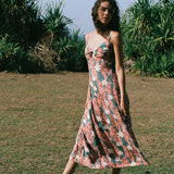 woman with brown hair wearing wearing a long maxi dress with knot tie neckline in a red ginger and tiare print