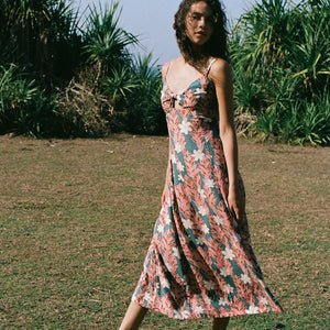 woman with brown hair wearing wearing a long maxi dress with knot tie neckline in a red ginger and tiare print