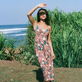 woman with brown hair wearing wearing a long maxi dress with knot tie neckline in a red ginger and tiare print