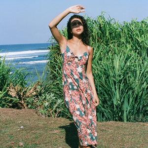 woman with brown hair wearing wearing a long maxi dress with knot tie neckline in a red ginger and tiare print