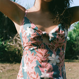 woman with brown hair wearing wearing a long maxi dress with knot tie neckline in a red ginger and tiare print