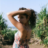 woman with brown hair wearing wearing a long maxi dress with knot tie neckline in a red ginger and tiare print