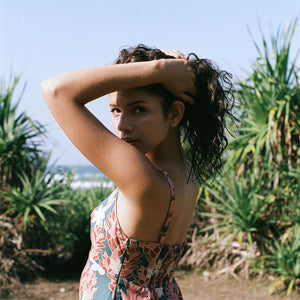 woman with brown hair wearing wearing a long maxi dress with knot tie neckline in a red ginger and tiare print
