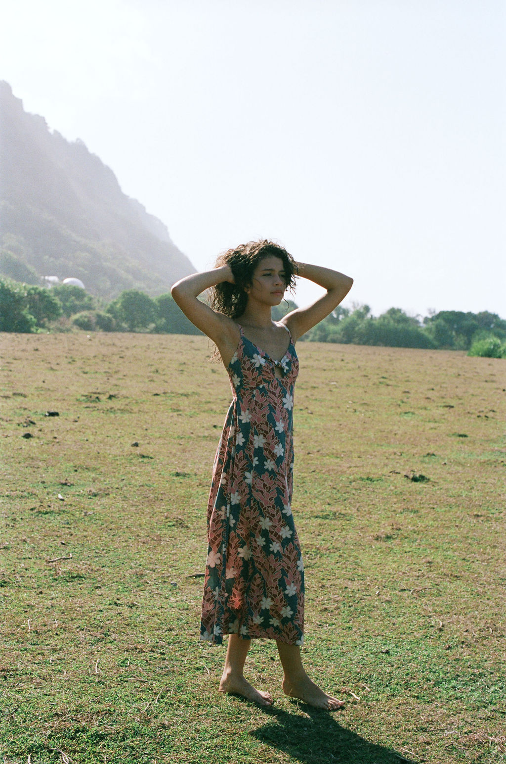 woman with brown hair wearing wearing a long maxi dress with knot tie neckline in a red ginger and tiare print