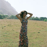 woman with brown hair wearing wearing a long maxi dress with knot tie neckline in a red ginger and tiare print