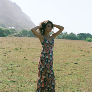 woman with brown hair wearing wearing a long maxi dress with knot tie neckline in a red ginger and tiare print