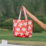 Woman with tote bag with beige and pink hibiscus print on orange red ground.