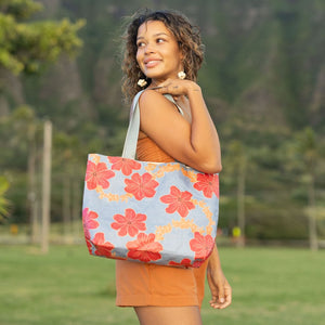 Woman with tote bag with red and orange floral print on light blue ground.