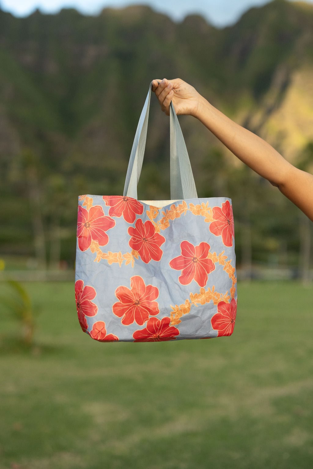 Tote bag with red and orange floral print on light blue ground.