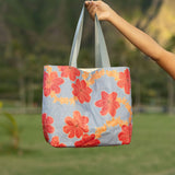 Tote bag with red and orange floral print on light blue ground.