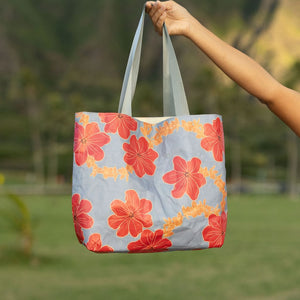 Tote bag with red and orange floral print on light blue ground.