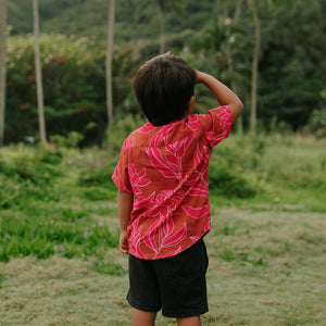 Boy in brown button up shirt with large pink floral print