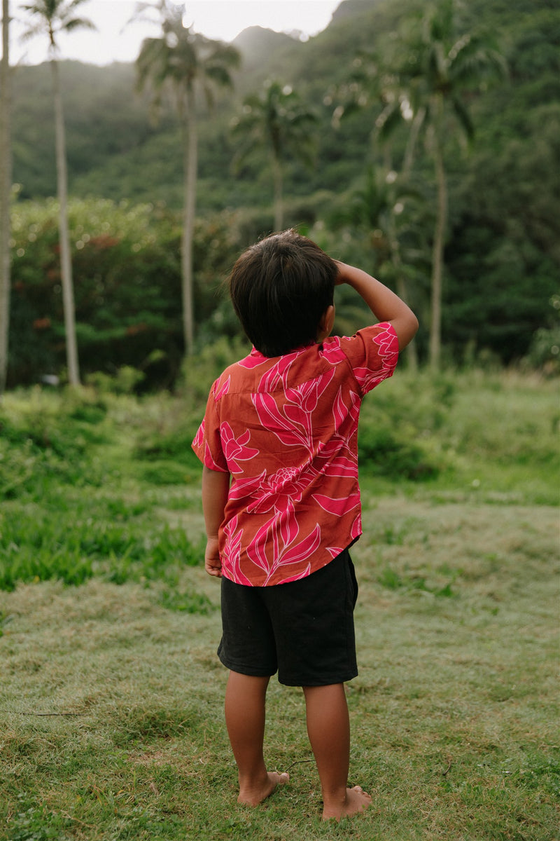 Boy in brown button up shirt with large pink floral print