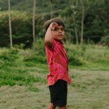 Boy in brown button up shirt with large pink floral print