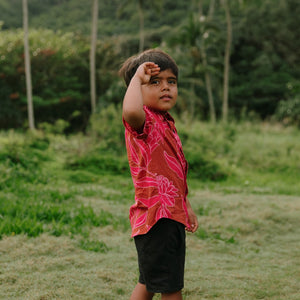Boy in brown button up shirt with large pink floral print